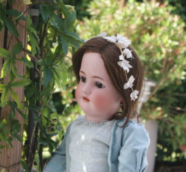 Antieke pop met bloemenkrans